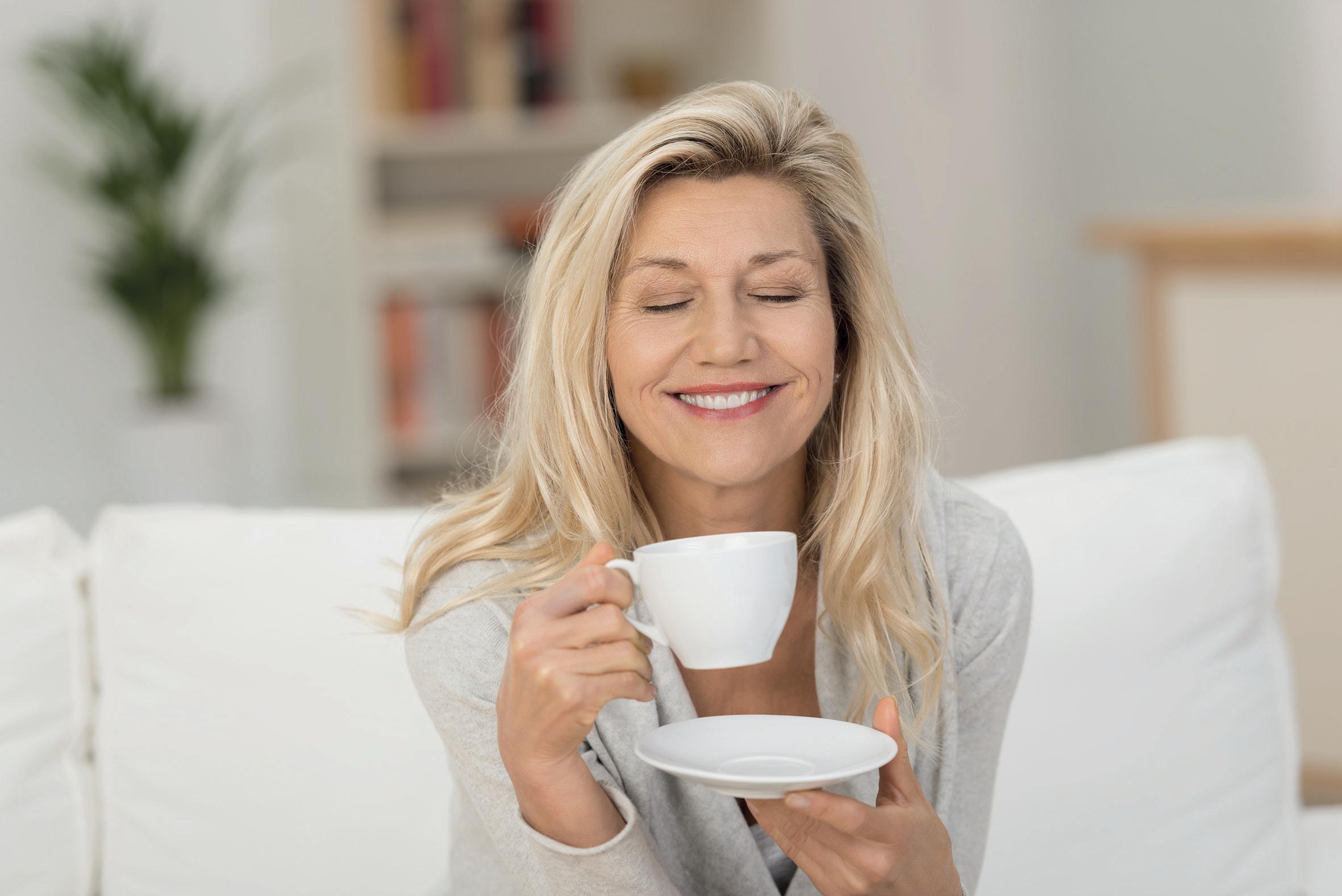 Frau genießt eine Tasse Tee auf ihrem Sofa